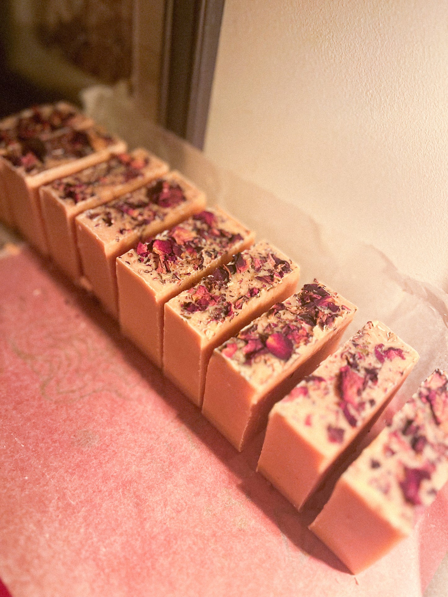 Row of pink soap bars with dried flowers on a pink surface