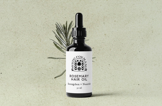 Bottle of rosemary hair oil with a dropper on a textured beige background