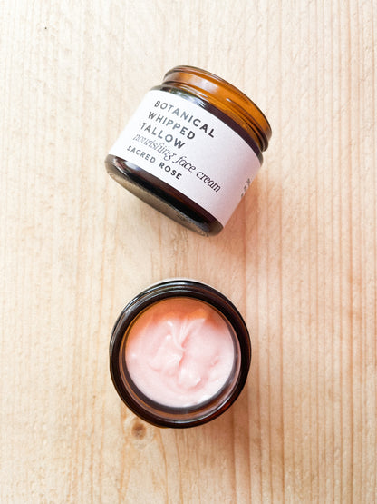 Two jars of botanical whipped tallow face cream on a wooden surface