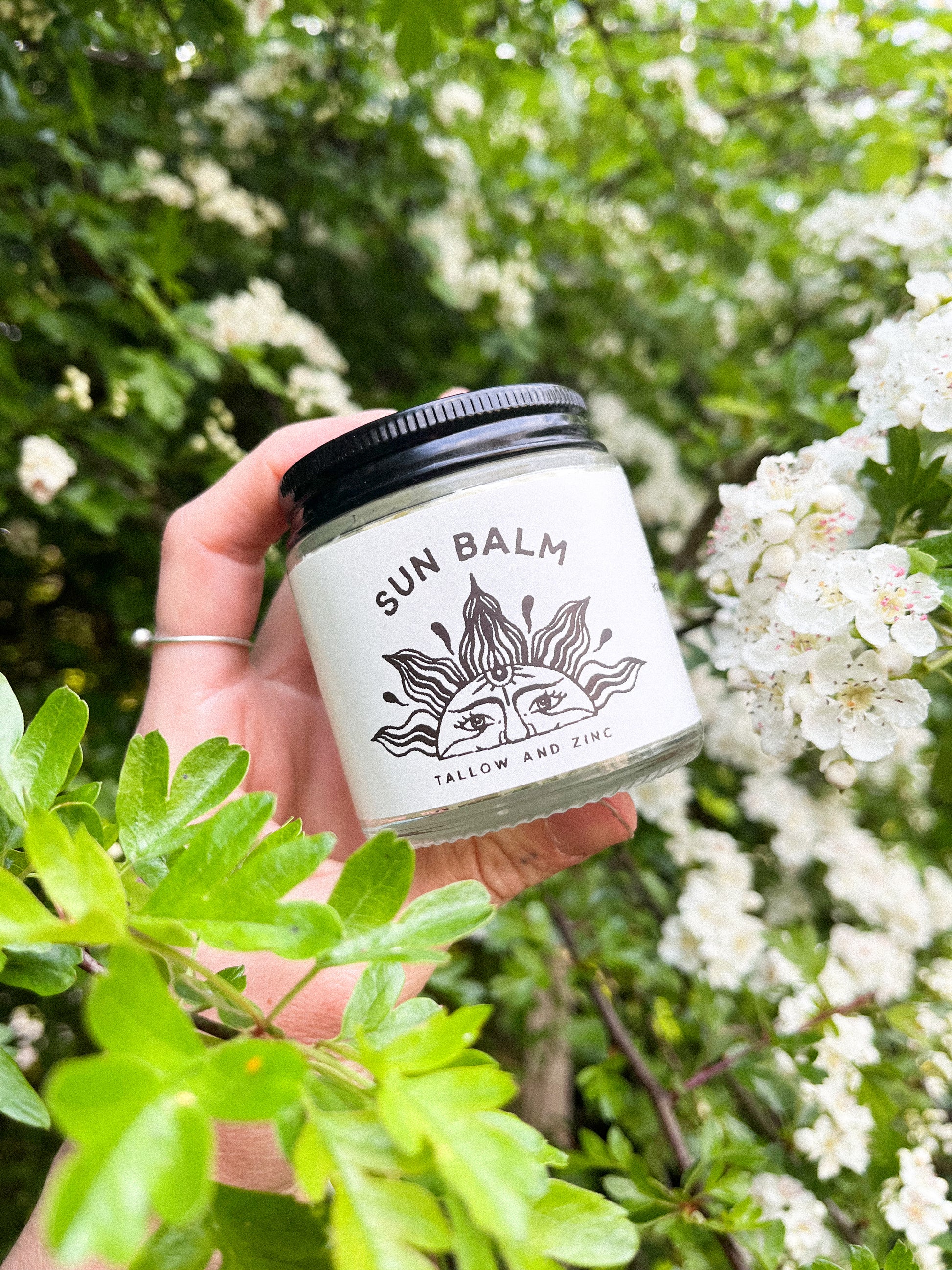 Glass jar of Tallow and zinc sunscreen outside with label on 